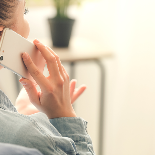 A woman holds a cell phone to her ear while having an animated conversation