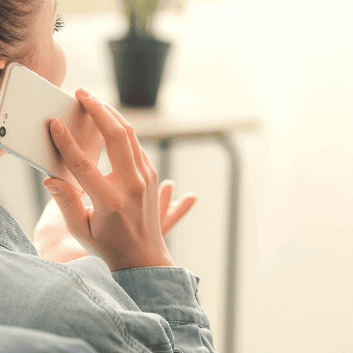A woman holds a cell phone to her ear while having an animated conversation