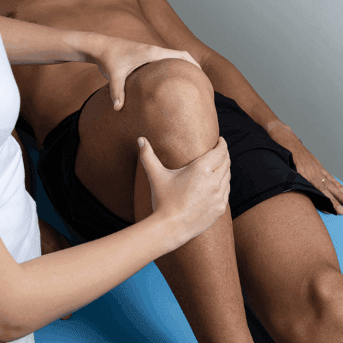 A patient is lying down and receiving hands-on physical therapy treatment for knee pain